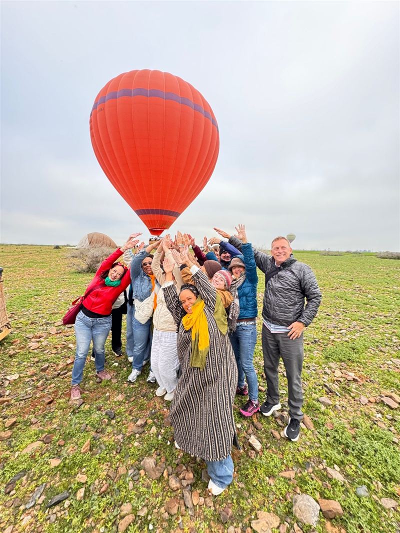 Famiglia e amici che festeggiano davanti a una mongolfiera rossa