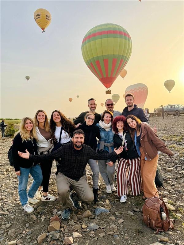 Gruppo di amici sorridenti davanti alle mongolfiere all'alba a Marrakech